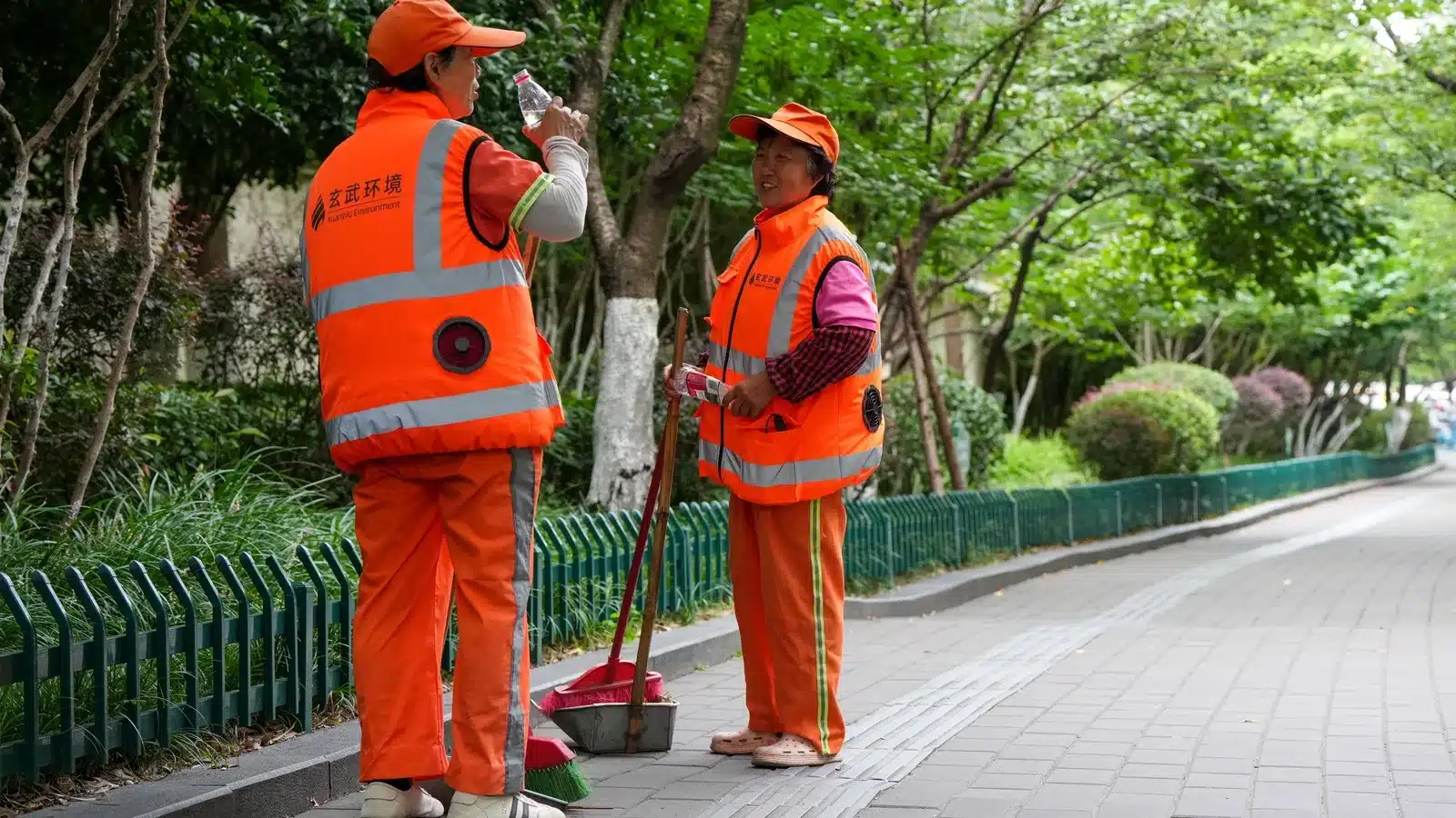 Nanjing sanitation workers wearing reflective fan-equipped cooling vests while working outdoors